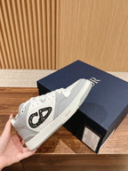 White and gray sneakers with black Dior lettering on the side, on shoebox