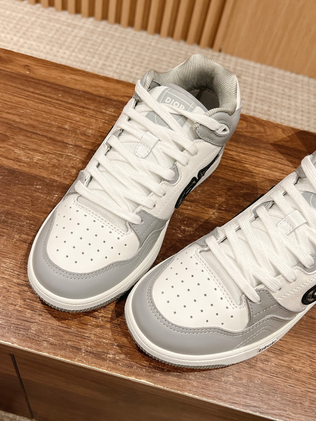 White and gray low-top sneakers with perforated toe and white laces