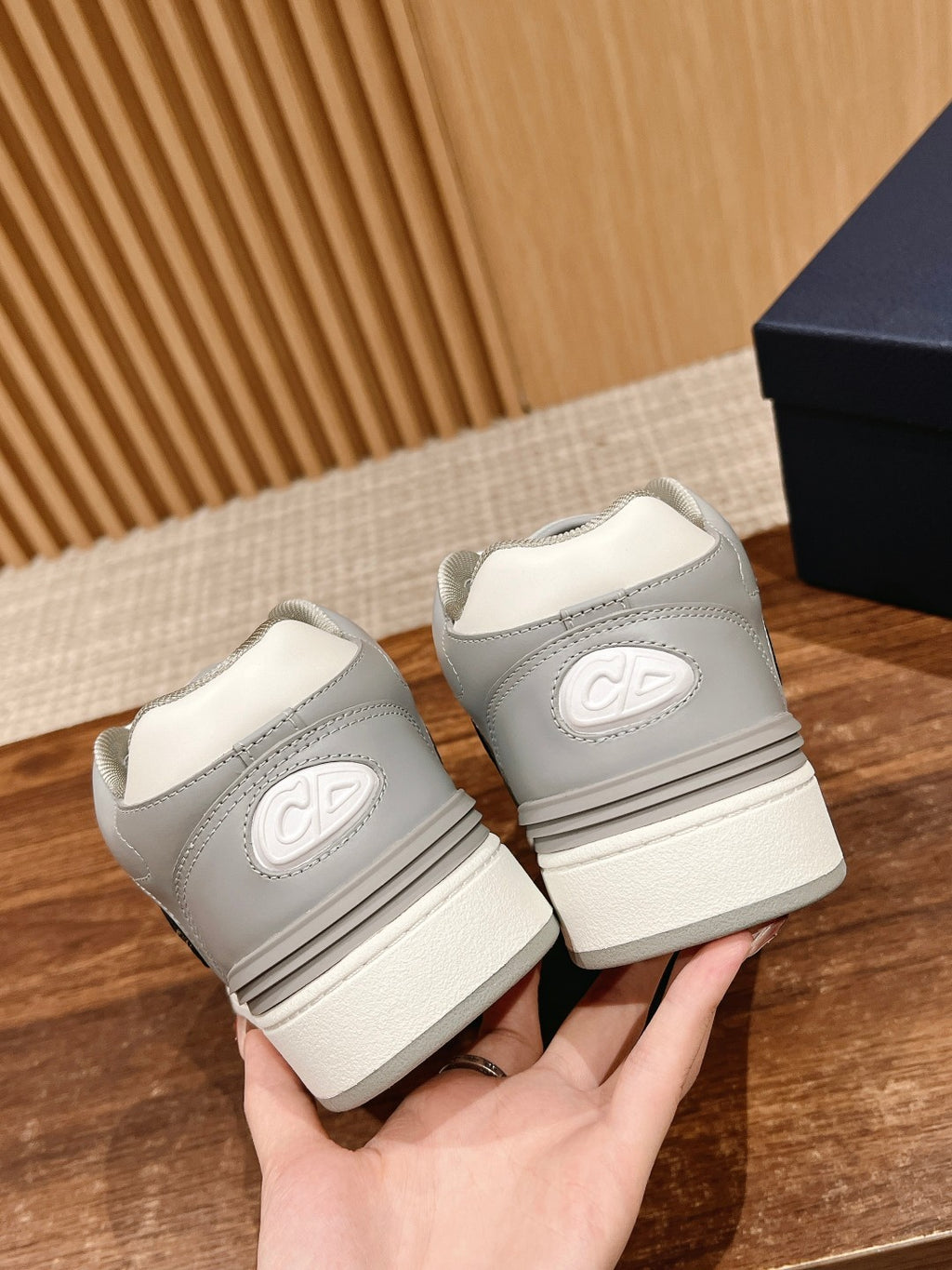 White and gray low-top sneakers, heel view with Dior logo on back tab