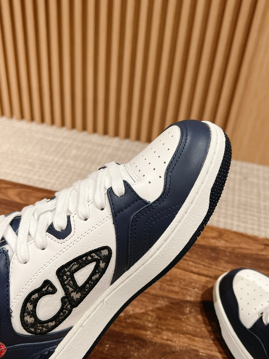 White leather low-top sneaker with navy overlays and large logo emblem