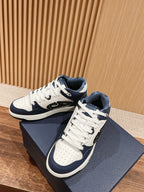 White-and-navy low-top sneakers with lace-up closure, placed on navy box
