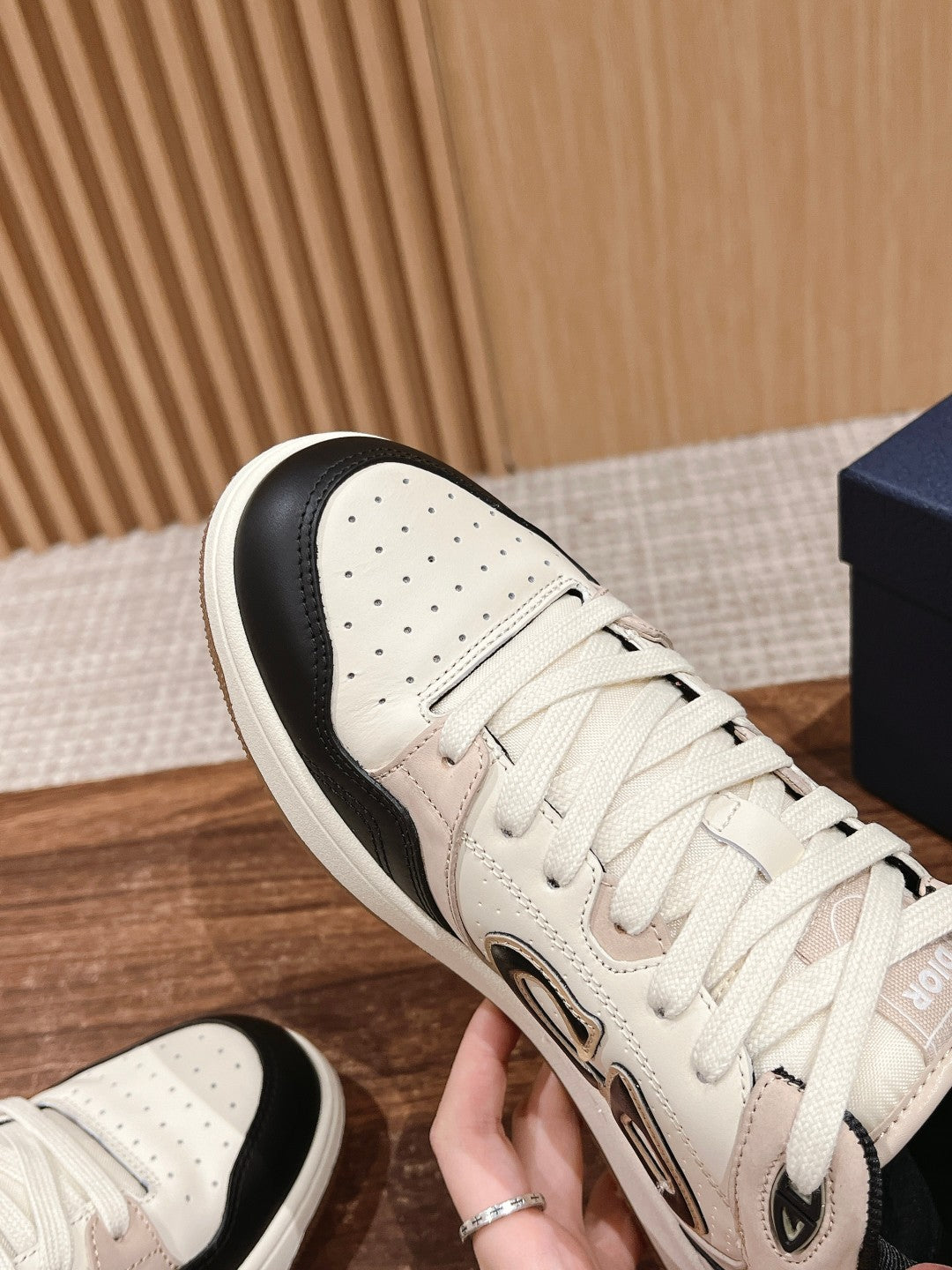 Close-up of cream and black lace-up sneaker upper with logo emblem