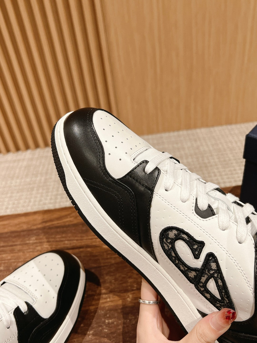Dior unisex sneakers close-up: white laces with black panel and textured side emblem