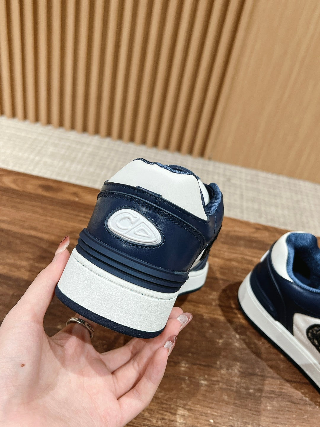 Back view of navy and white low-top sneakers with Dior logo patch