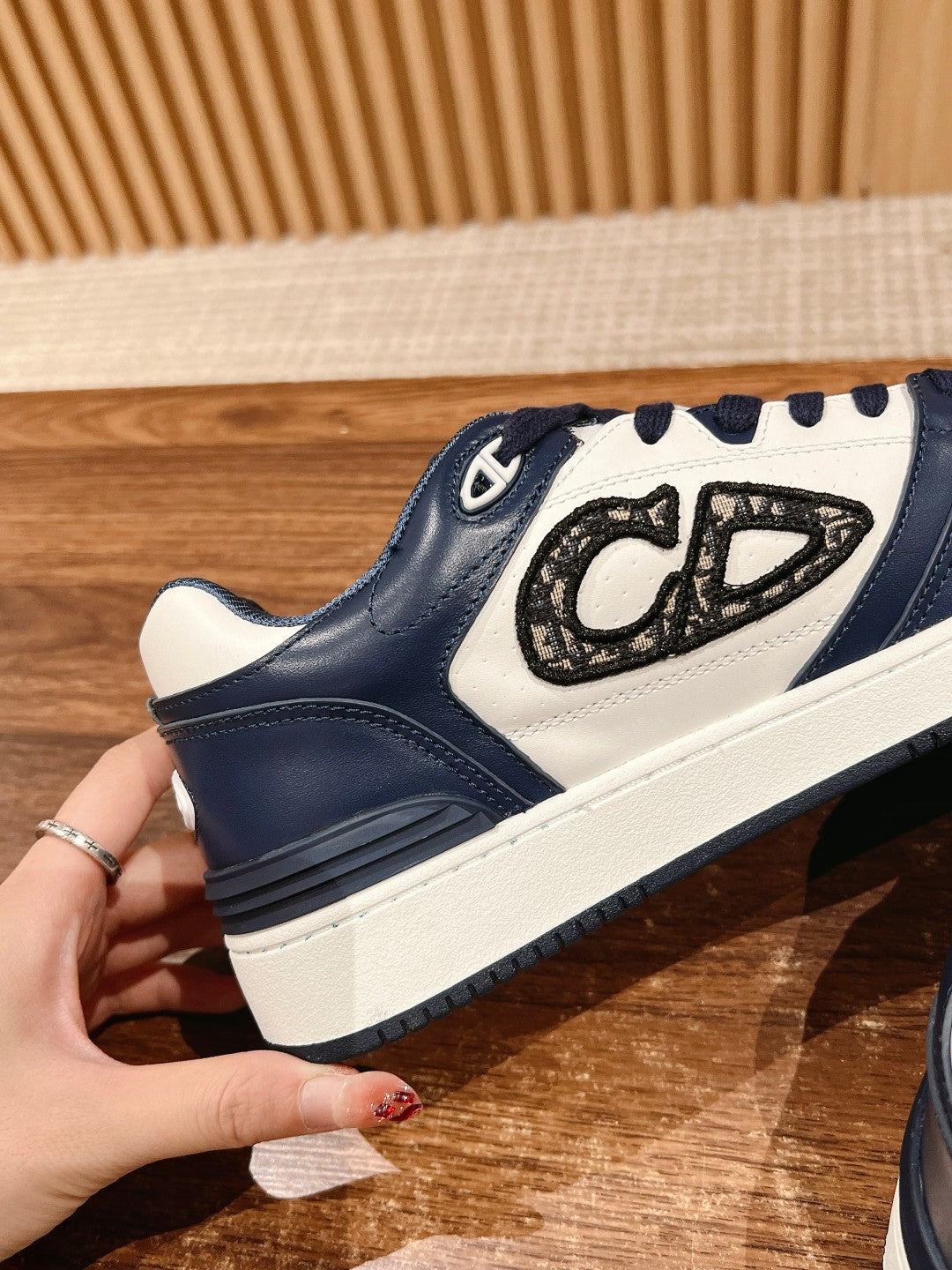Side view of navy and white low-top sneakers with lace-up and emblem