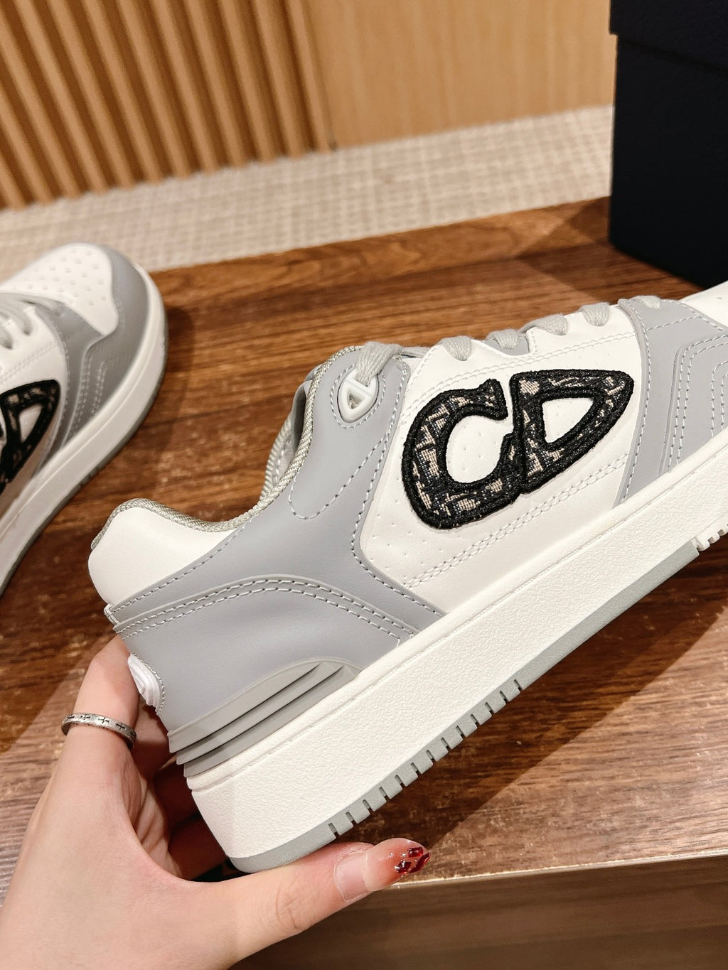 Dior unisex sneakers close-up: white and gray uppers with black embroidered logo