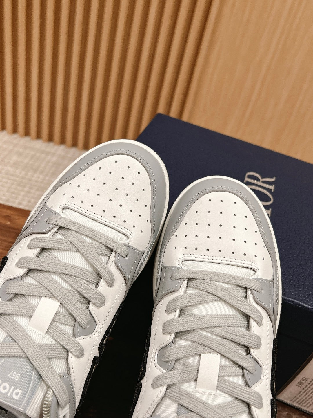 Dior unisex sneakers showing perforated toe and gray laces on white and gray uppers