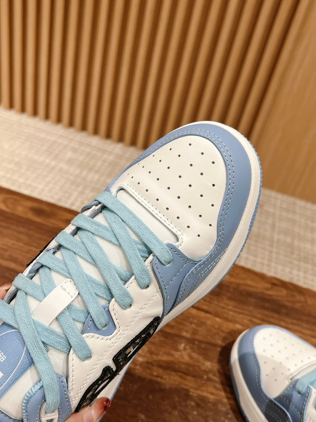 Light blue Dior low-top sneaker close-up, white perforated toe and light blue laces.