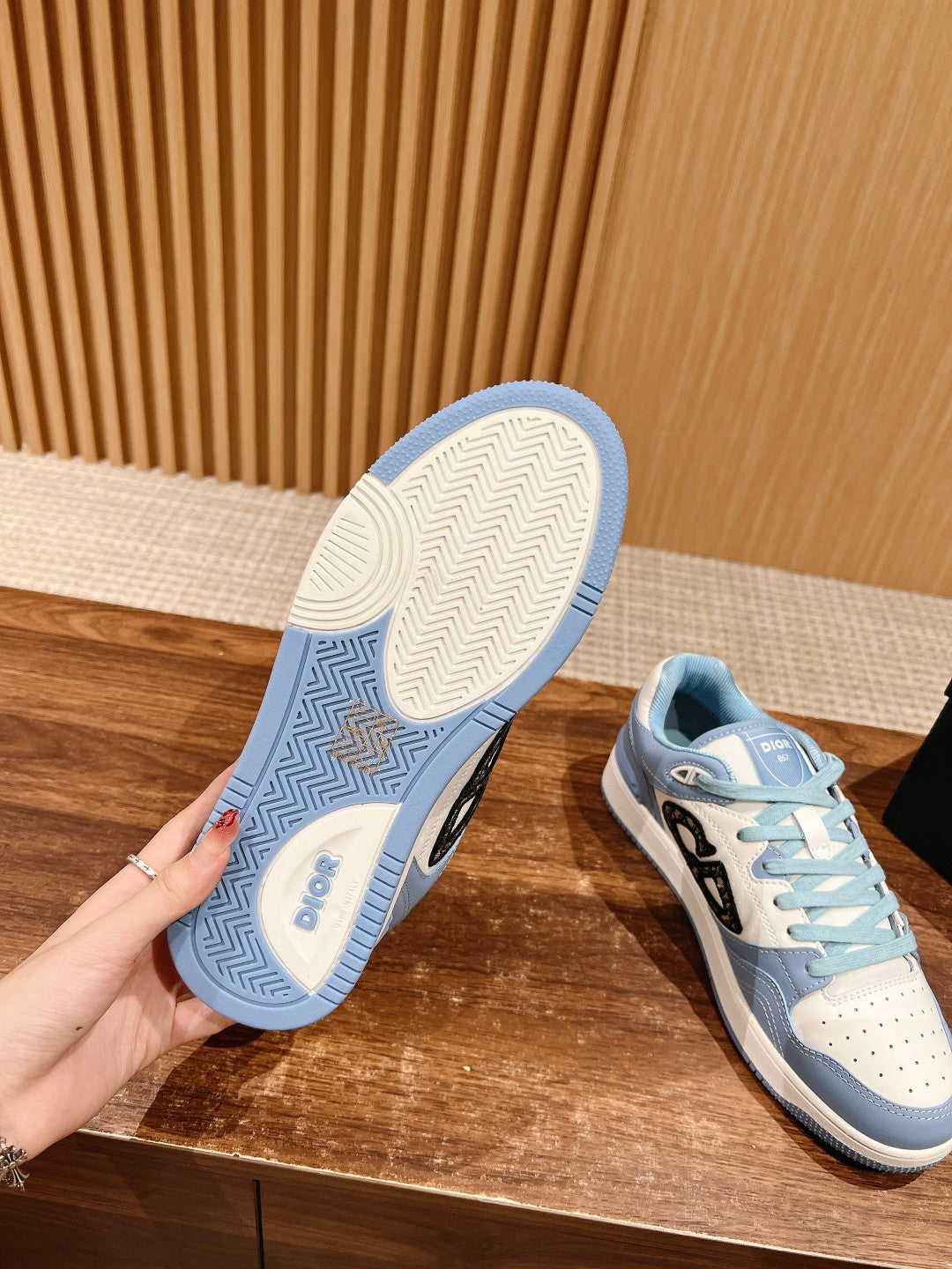 Light blue Dior low-top sneaker with textured outsole and black side logo, lace-up.