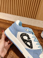 Light blue Dior low-top sneaker side view, black logo and white midsole, lace-up.