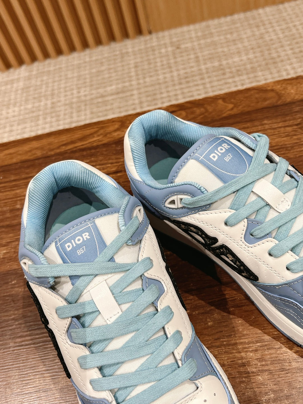 Light blue Dior low-top sneakers close-up, Dior tongue label and black side logo.