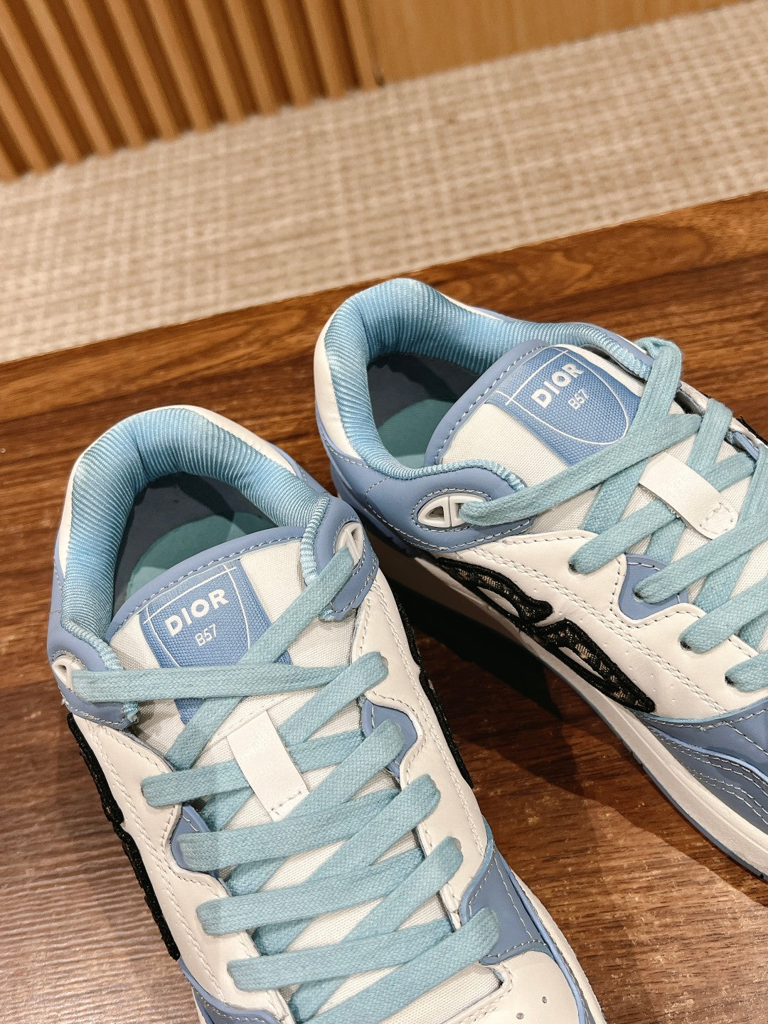 Light blue Dior low-top sneakers close-up, Dior tongue label and black side logo.