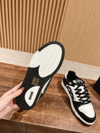 Pair of Dior sneakers showing soles: textured tread with black sidewall and white base