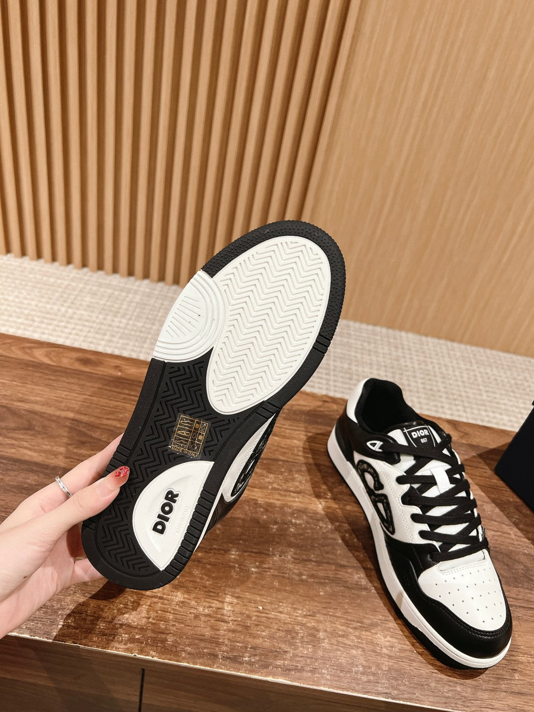 Pair of Dior sneakers showing soles: textured tread with black sidewall and white base