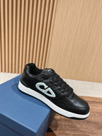 Black low-top sneaker with white midsole and light blue side logo detail