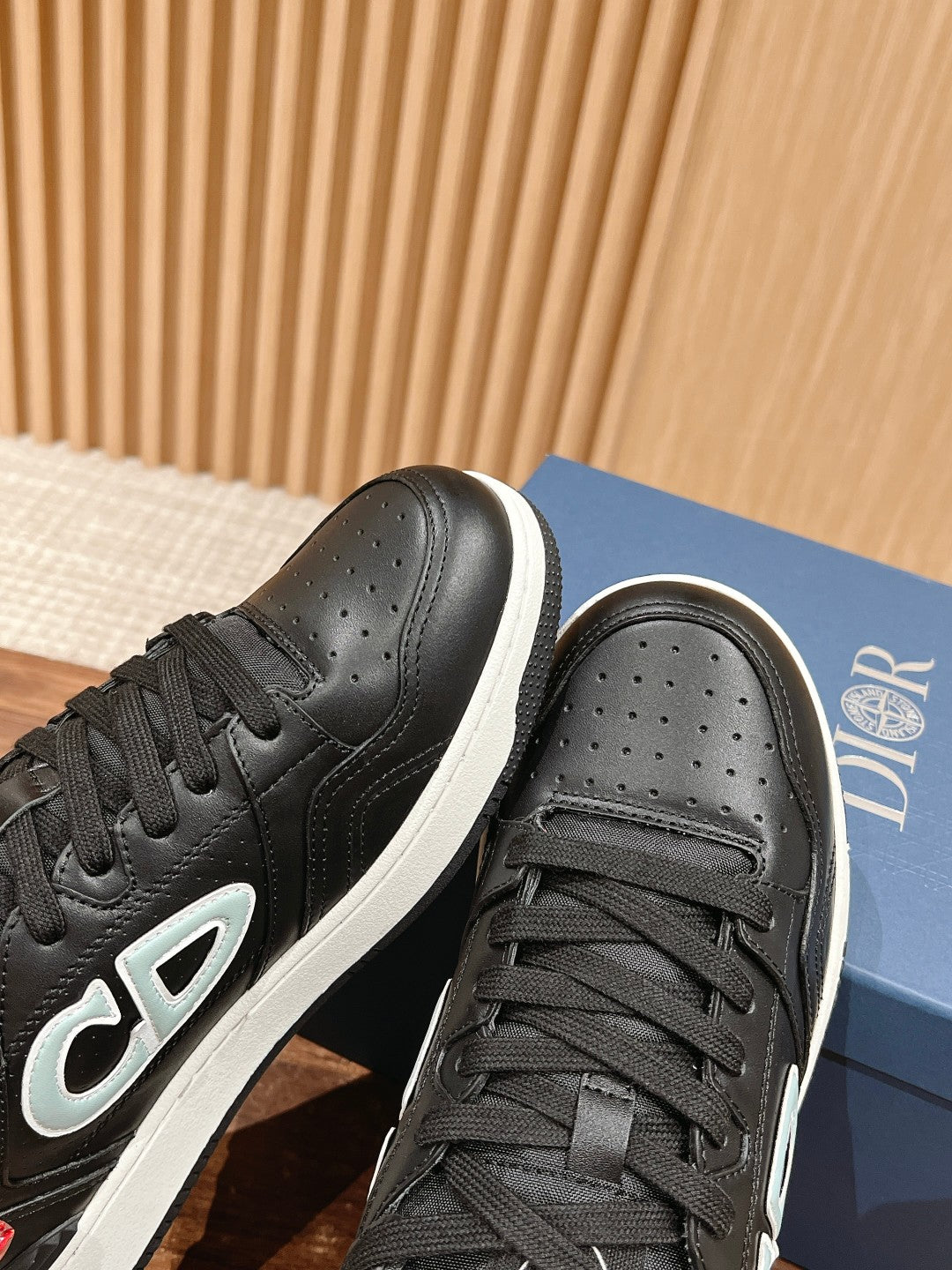 Black low-top sneakers close-up: laces, perforated toe, Dior side logo