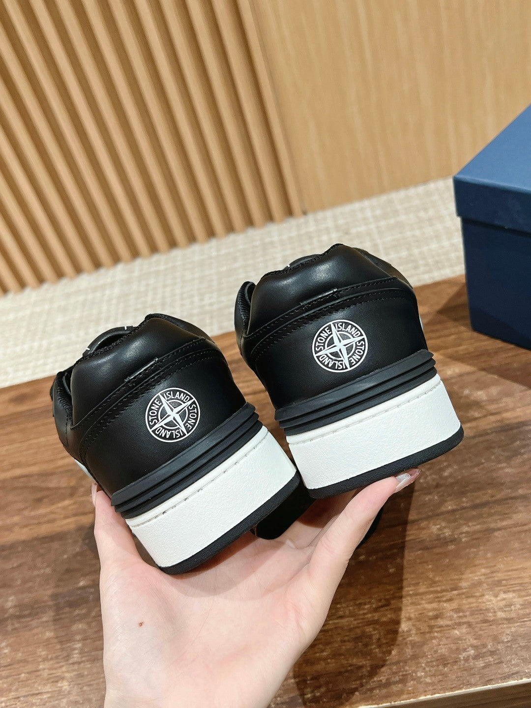 Black low-top sneakers back view with white sole and circular heel logo