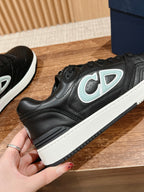 Black low-top sneaker close-up with light blue and white side logo, white sole
