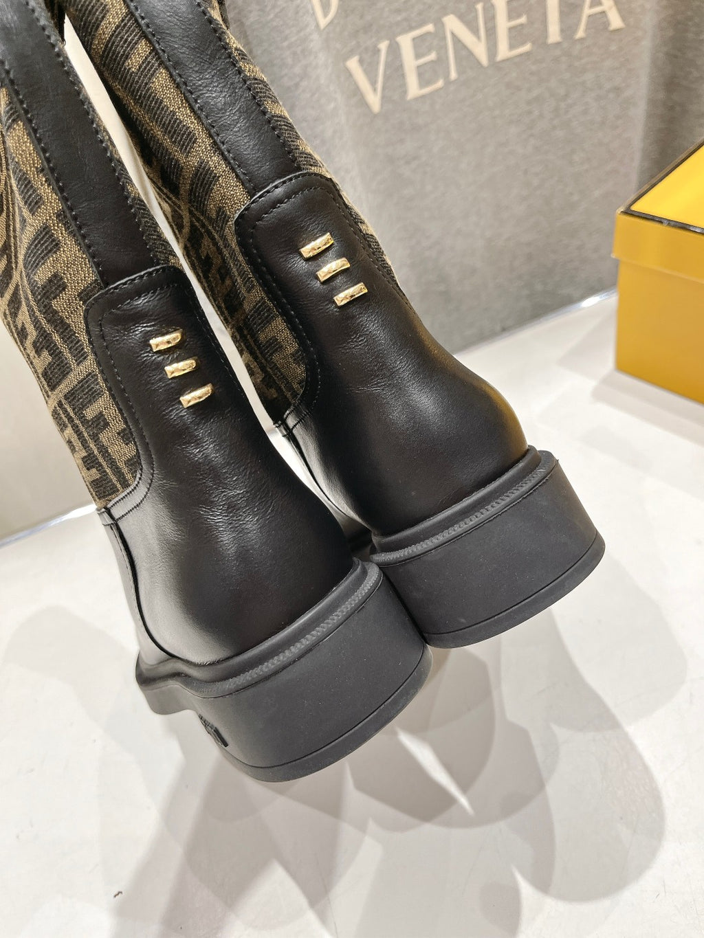 Fendi FF-logo boots with stacked rubber heel and black leather back strap.