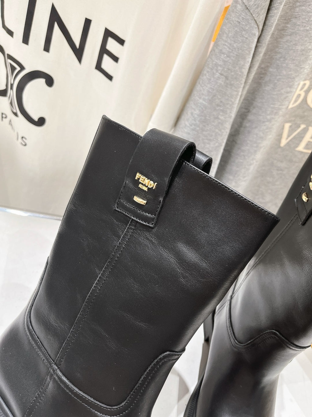 Fendi women’s black leather mid-calf boot, close-up of side strap and label.