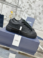 Black lace-up sneakers with embossed pattern and Dior logo, on blue box