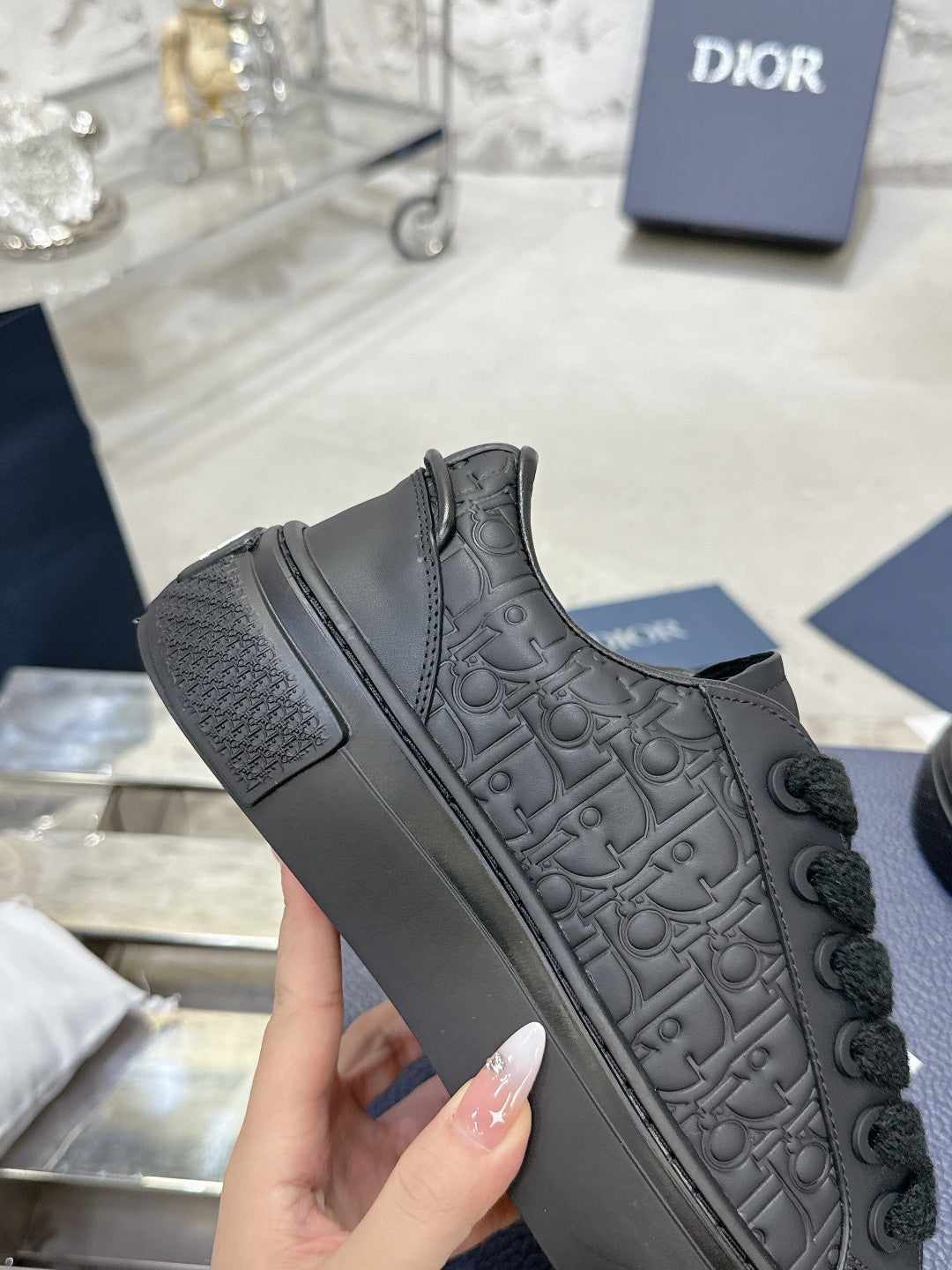 Black lace-up low-top sneaker with embossed pattern and cushioned rubber sole