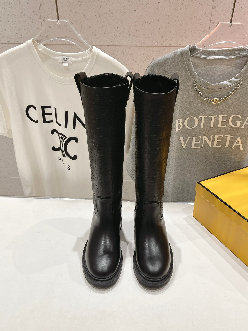 Black knee-high boots with side pull tabs and rounded toe, flat sole.