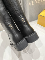 Black knee-high boots with embossed monogram panels and stitched outsole edge.