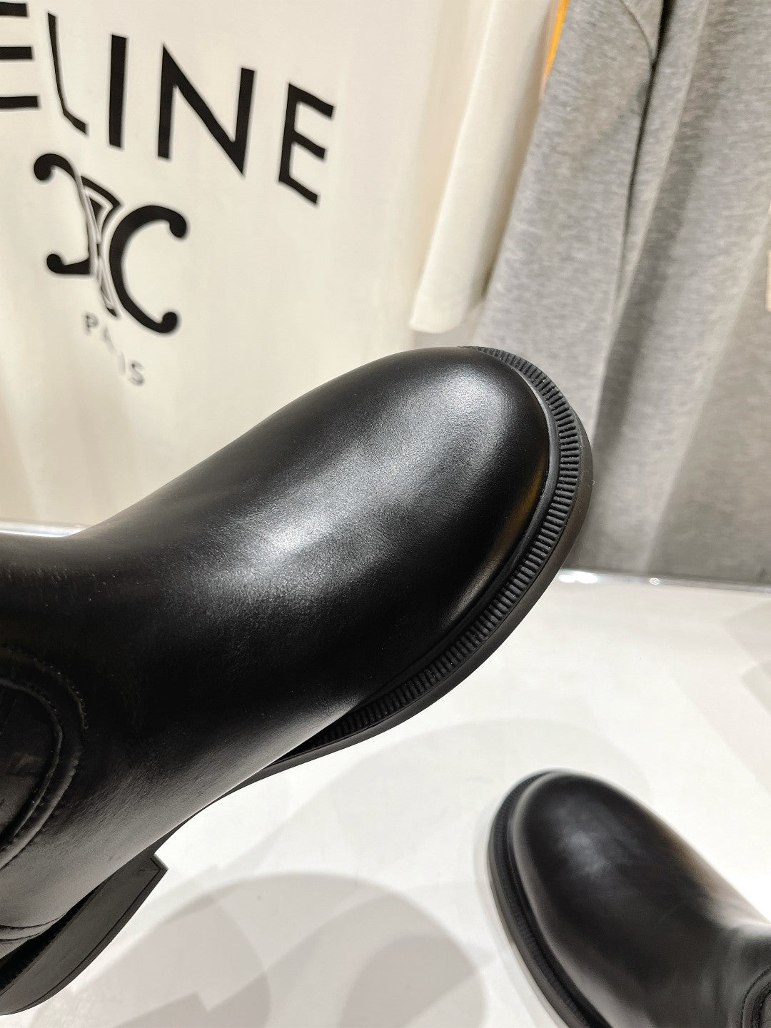 Black knee-high boot with smooth leather finish and ribbed welt edge.