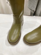 Olive green knee-high boots with smooth rounded toe and ribbed outsole edge.