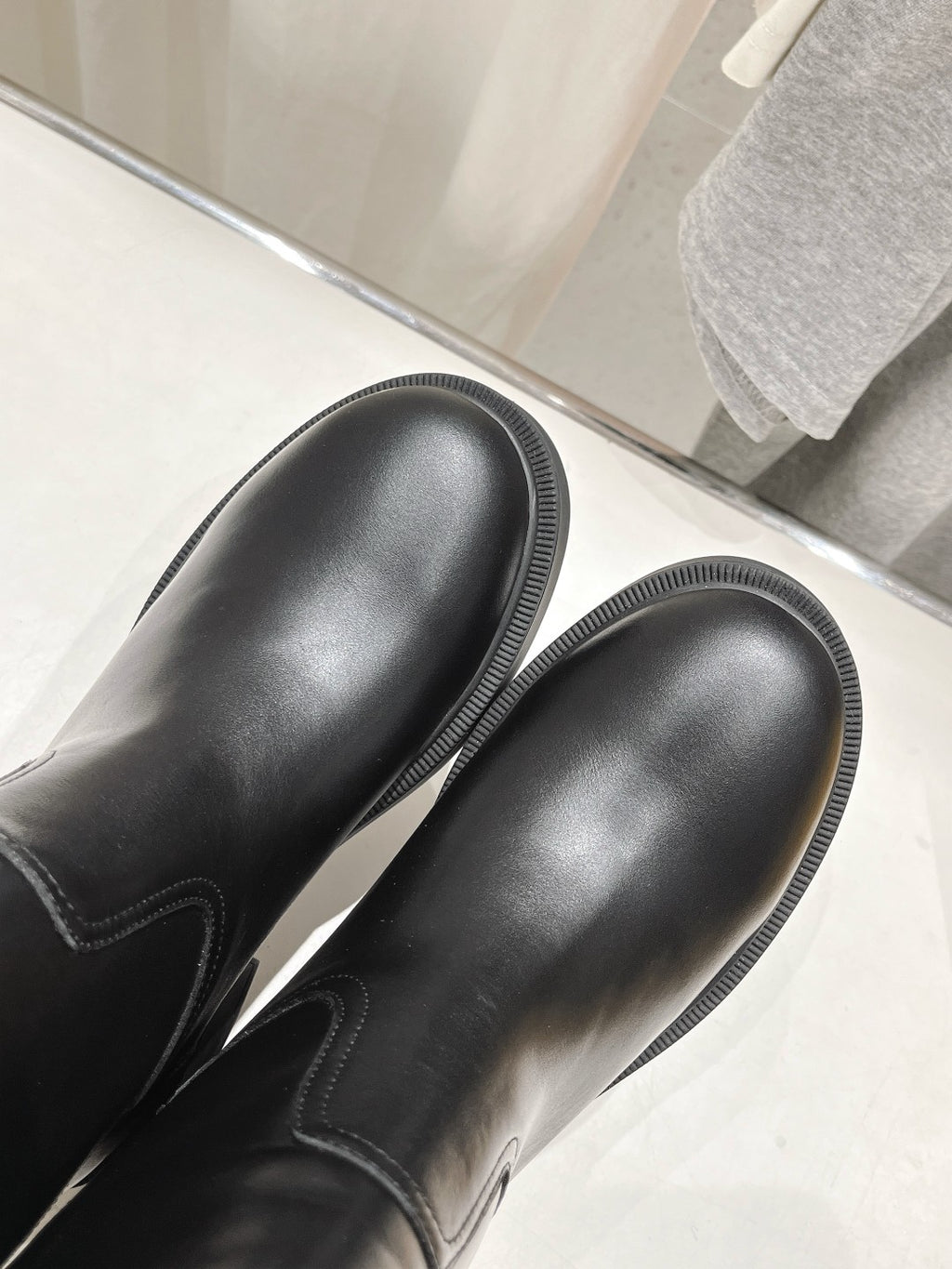 Black leather boot toes with ribbed stitching and rounded shape