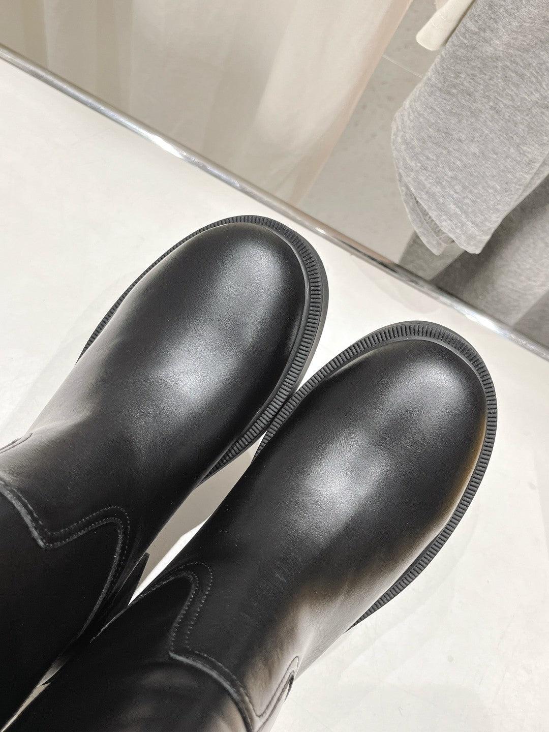 Black leather boot toes with ribbed stitching and rounded shape