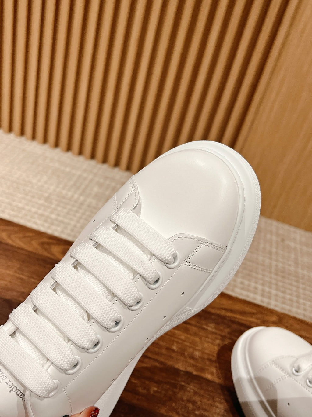 Close-up of white sneaker tongue and laces with stitched panels
