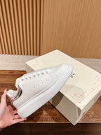 White lace-up sneakers with perforated toe and padded sole