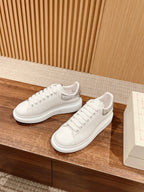 White low-top lace-up sneakers with textured side panel and perforated toe