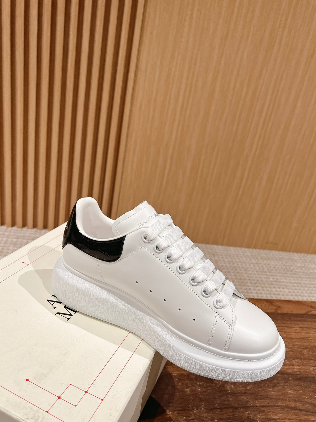 White low-top sneakers with black interior collar and lace-up eyelets