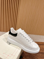 White low-top sneakers with black interior collar and lace-up eyelets