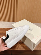White low-top sneakers with perforated toe and black heel panel