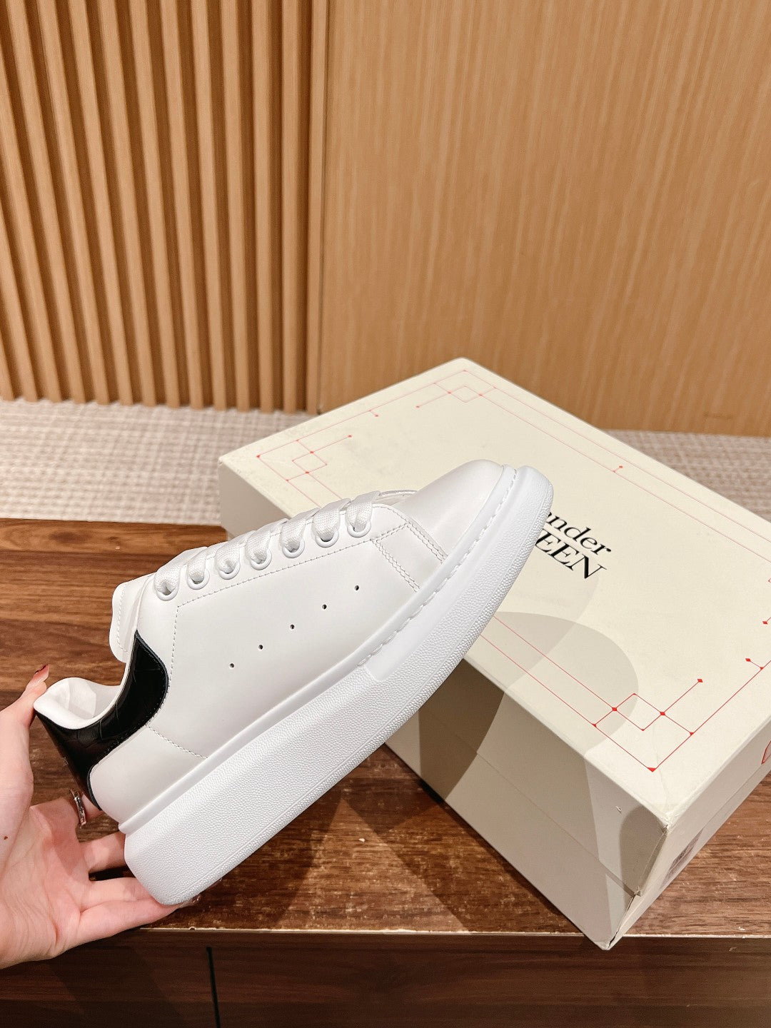 White low-top sneakers with perforated toe and black heel panel