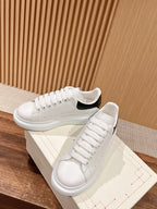 White low-top sneakers with black heel accent and padded tongue