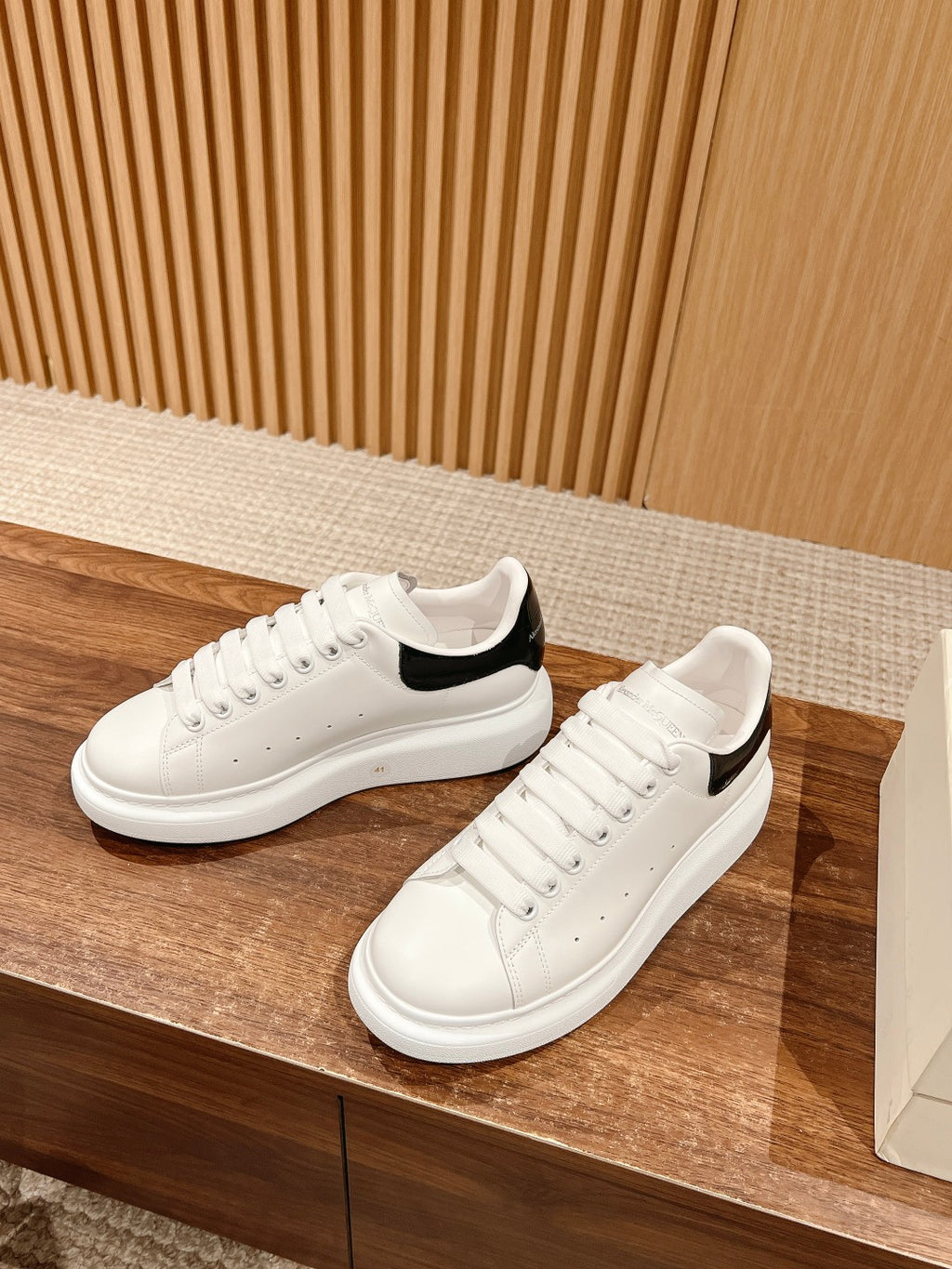White low-top sneakers with black collar lining and lace-up design