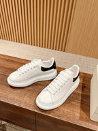 White low-top sneakers with black collar lining and lace-up design