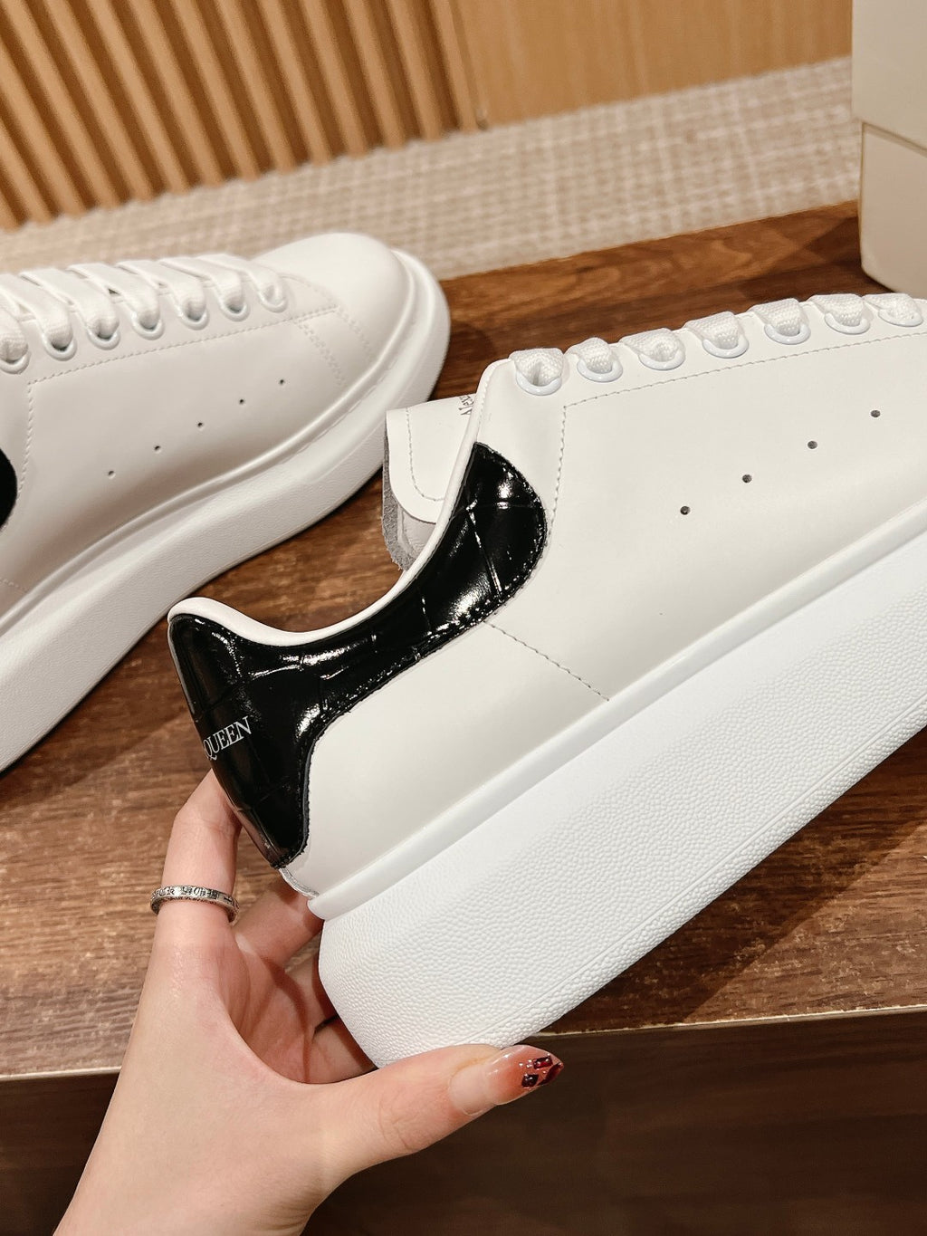 White leather sneakers with glossy black heel and lace-up forefoot