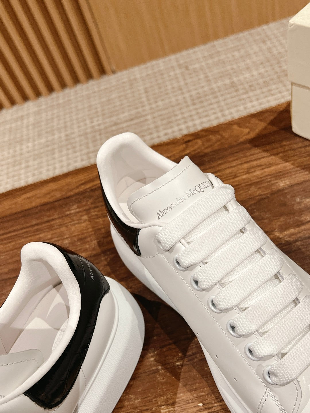 White low-top sneakers with black heel stripe and lace-up closure