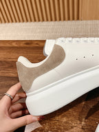 Close-up of white sneakers with beige suede quarter panel and lace-up eyelets