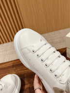 Side view of white sneaker with beige suede accent and lace-up stitching