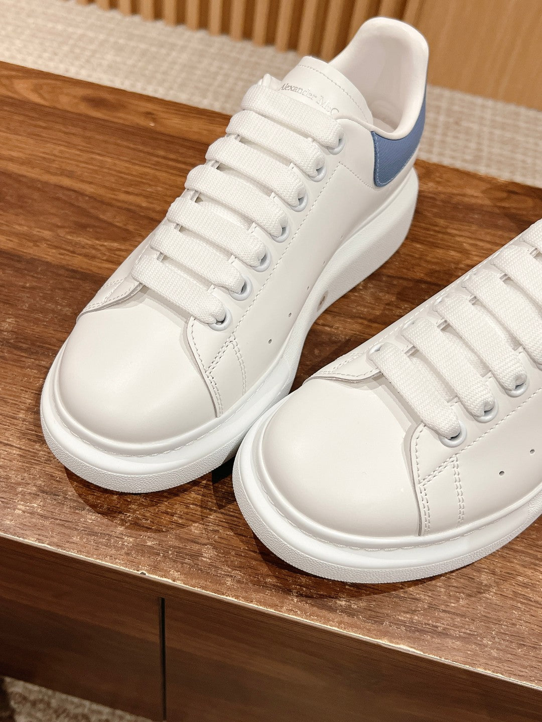 Alexander McQueen white low-top sneakers with blue heel, close-up of laces and side