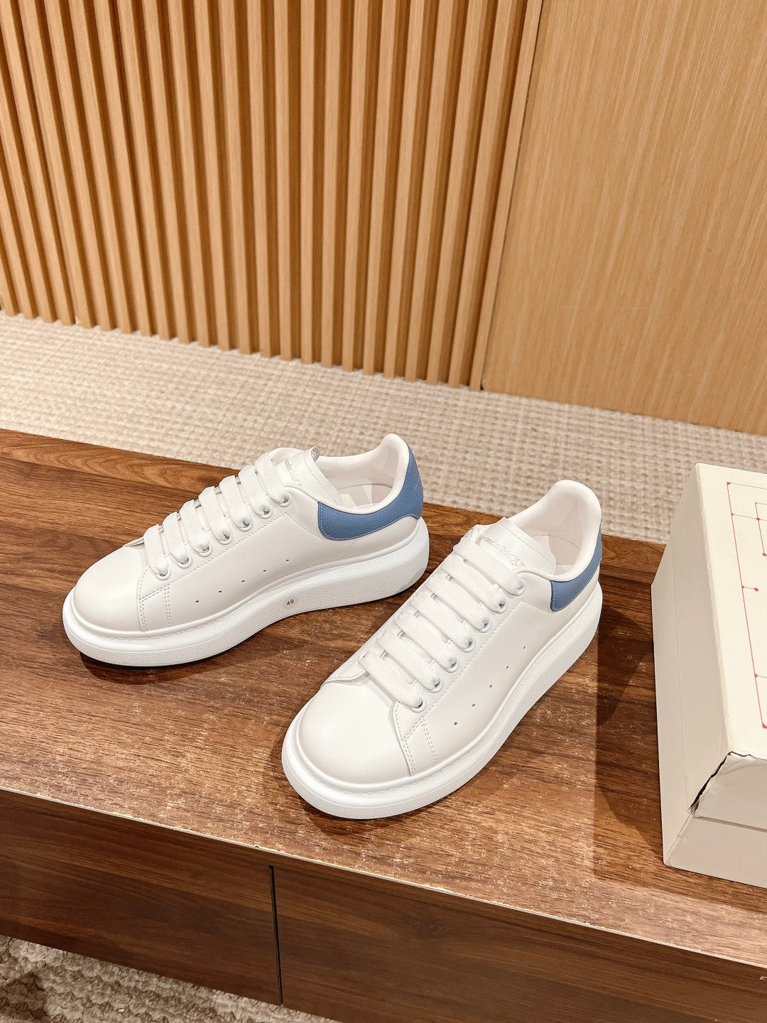 Alexander McQueen white and blue lace-up sneakers on display with shoe box