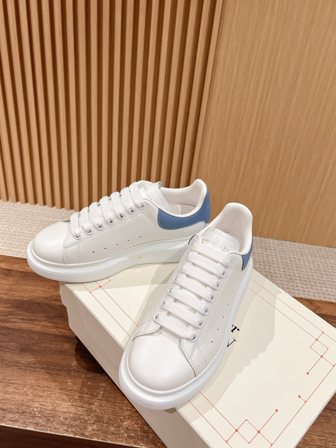 Alexander McQueen white sneakers with blue heel trim, lace-up, on top of a box