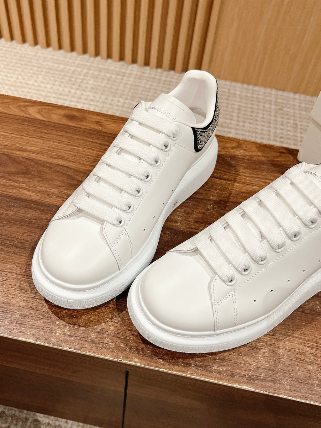 Two white sneakers with black heel logo patch and lace-up design